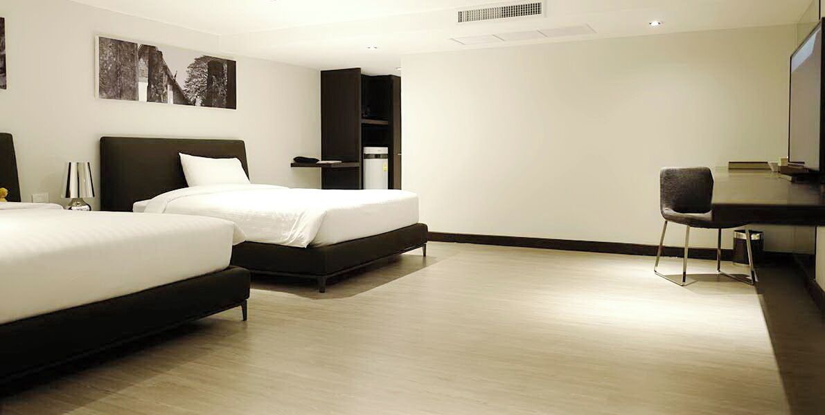 Ein Hotelzimmer mit zwei Betten, einem Schreibtisch, einem Stuhl und einem Fernseher.