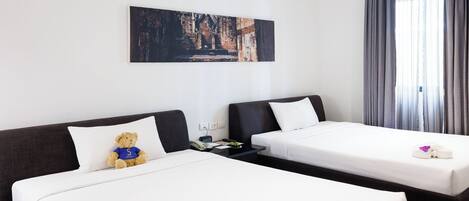 Habitación de hotel con dos camas, un cuadro en la pared y una ventana con cortinas.