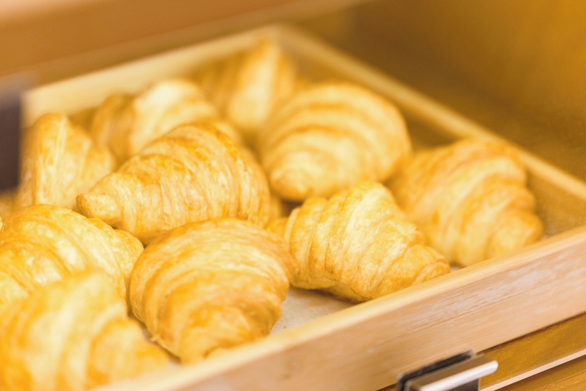 A wooden tray with several golden-brown pastries.