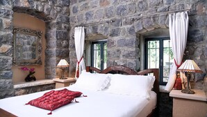 A stone-walled bedroom with a bed, two bedside lamps, and a window with curtains. - Shirat Hayam - Boutique Hotel (Tiberias)