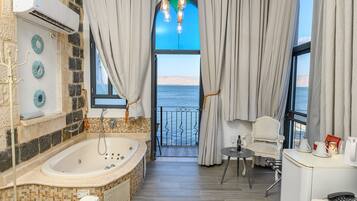 Un baño con bañera, ducha y vistas al mar.