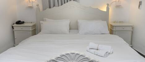 A neatly made bed with white linens, two bedside tables with lamps, and a telephone on the left table.