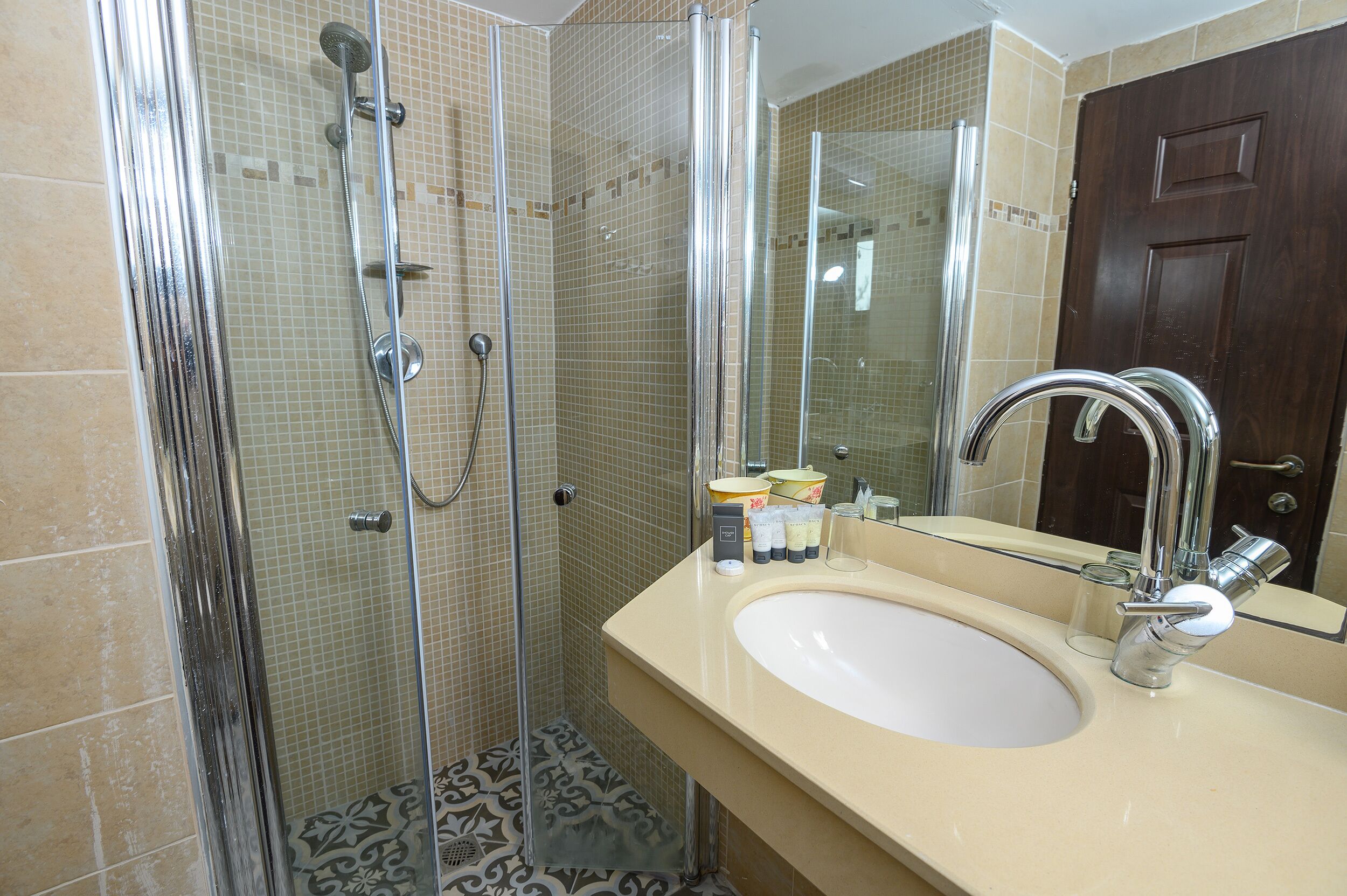 A bathroom with a glass-enclosed shower, a sink with a mirror, and a door.
