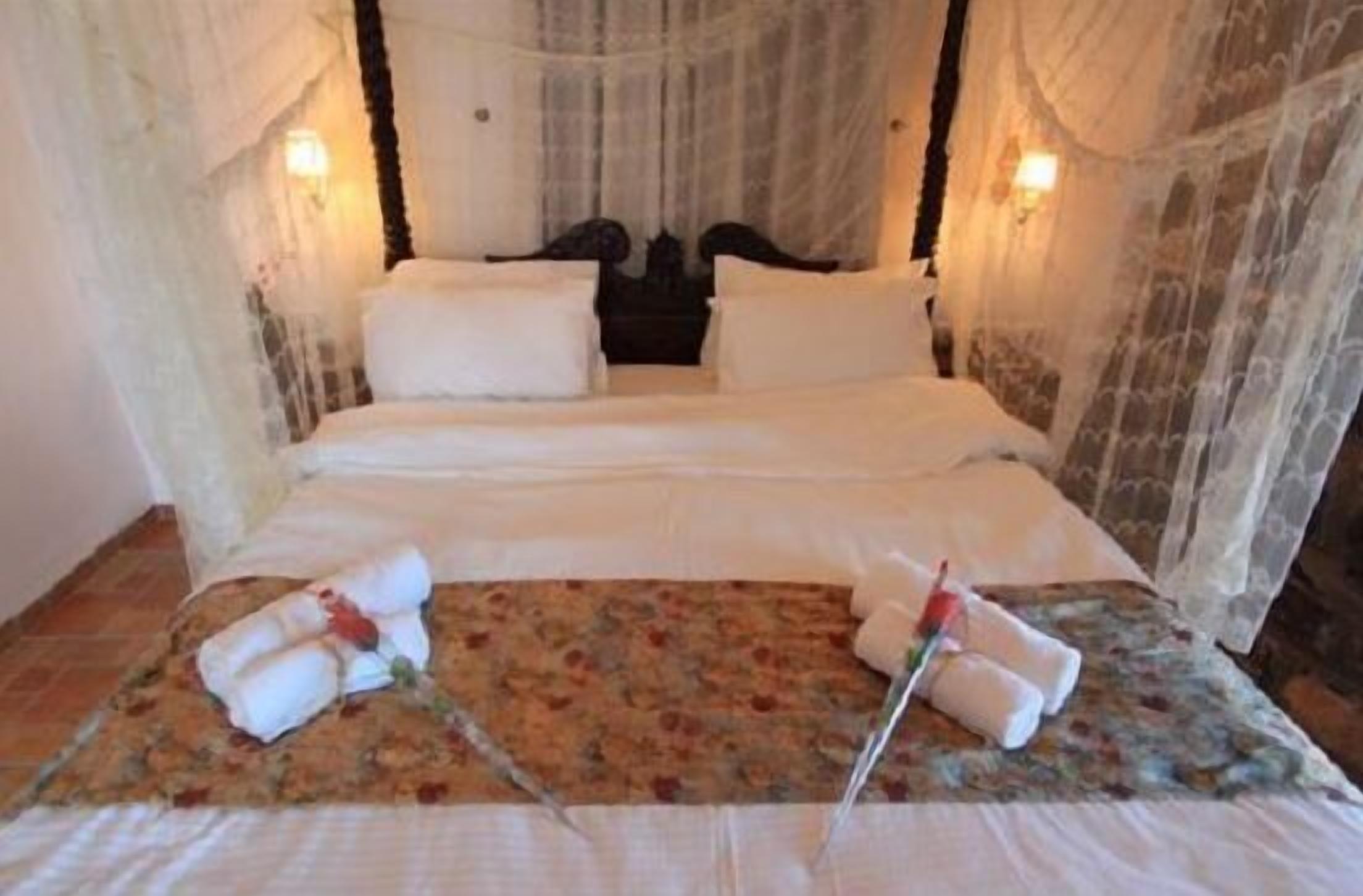 A bed with white linens, two pillows, and a floral-patterned bedspread.