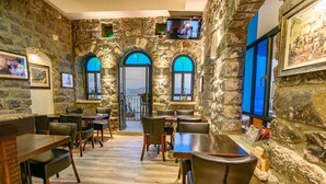 A restaurant with stone walls, arched windows, and wooden tables and chairs. - Shirat Hayam - Boutique Hotel (Tiberias)