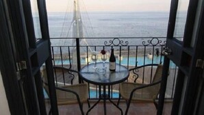 A balcony with a table and chairs, overlooking a pool and the sea. - Shirat Hayam - Boutique Hotel (Tiberias)
