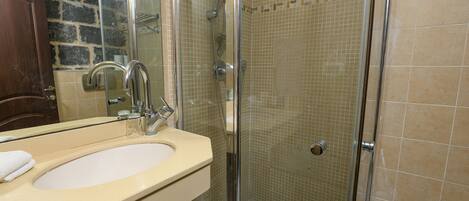 A bathroom with a beige sink, a mirror, and a shower with a glass door.