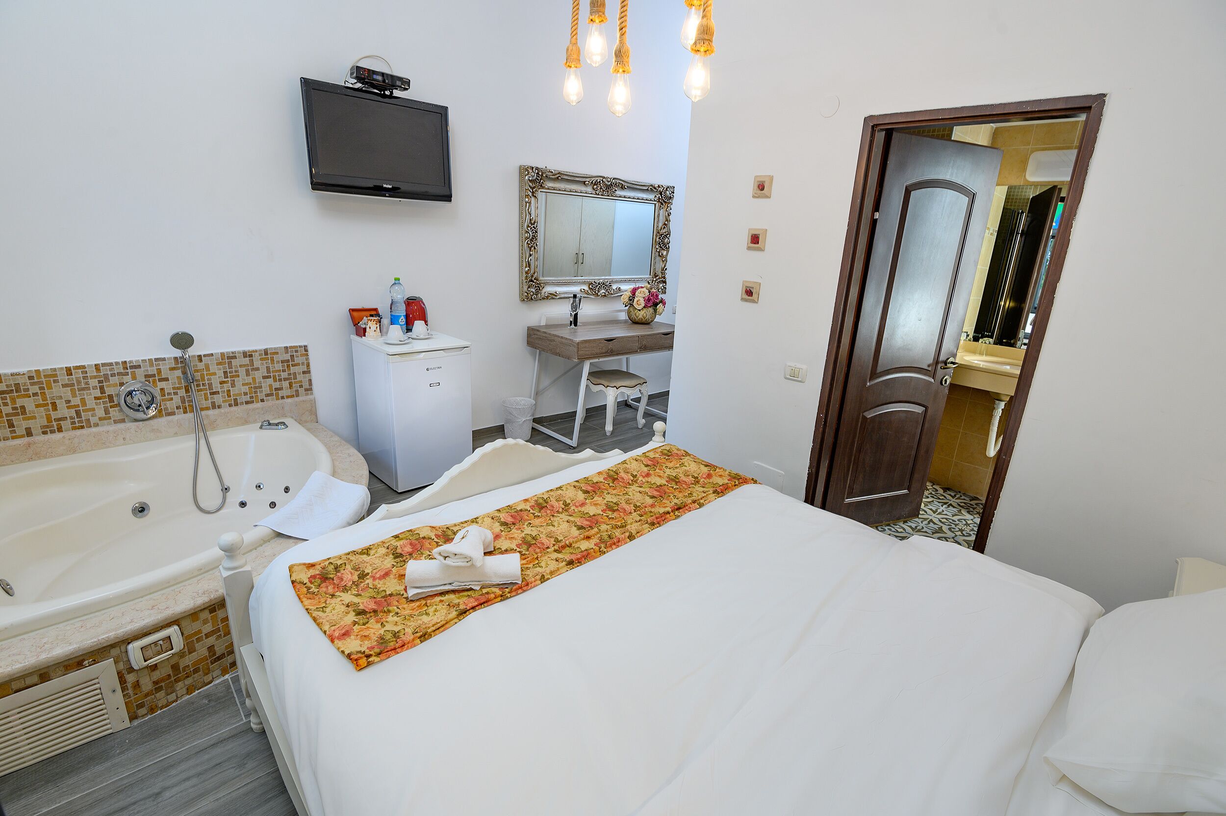 Une chambre d’hôtel avec un grand lit, une salle de bain avec baignoire, un bureau et un miroir.