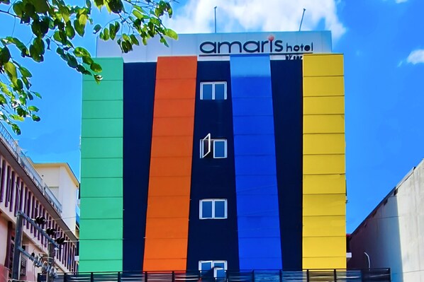 Um hotel com vários andares, apresentando um esquema de cores vertical em tons de verde, laranja, azul e amarelo.