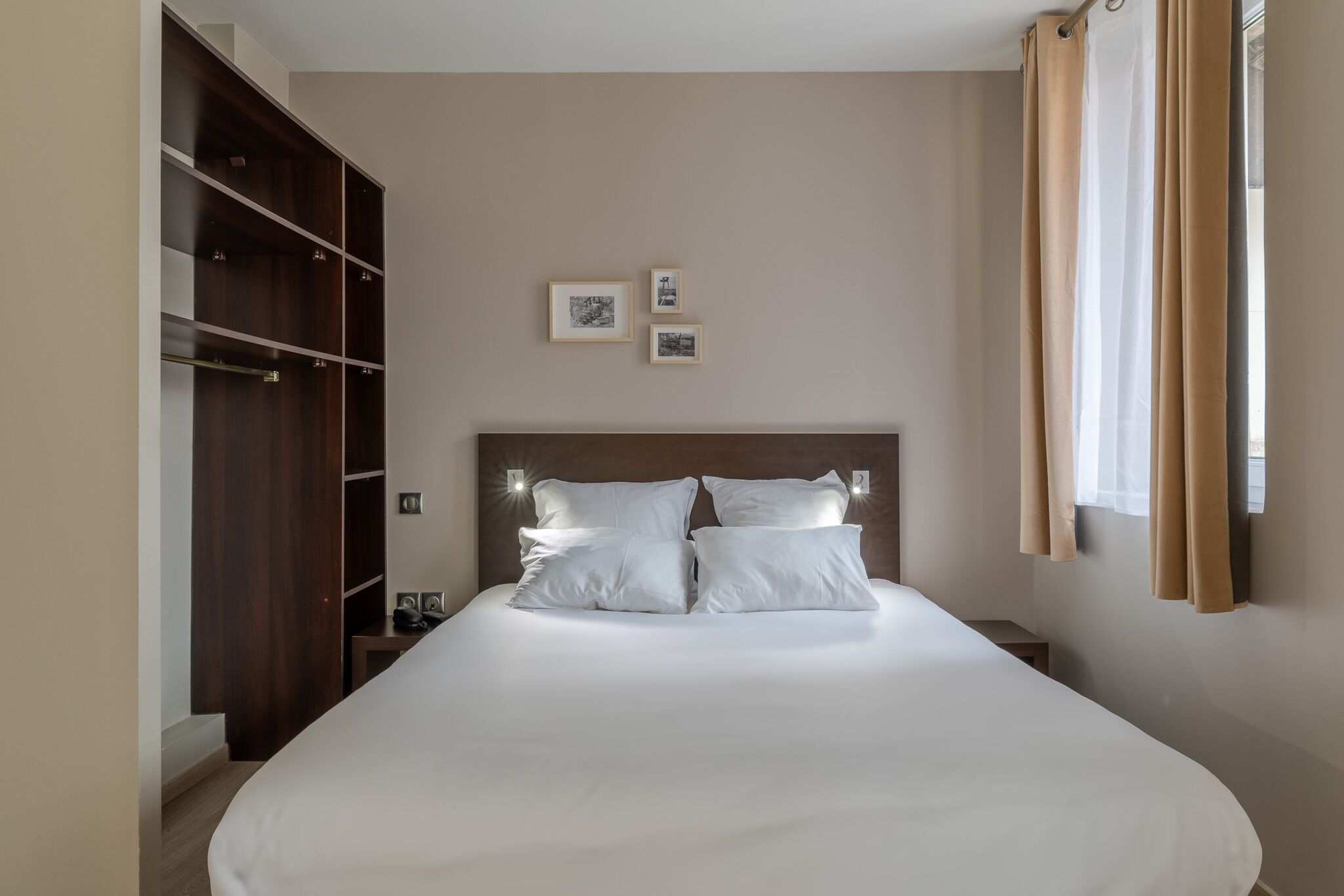 Un dormitorio con una cama grande, un armario y dos cuadros colgados en la pared.