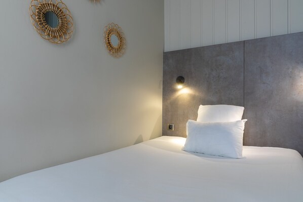 A modern bedroom with a large bed, a wall-mounted light, and decorative wall art.