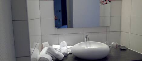 Een badkamer met een wit wastafel, een spiegel en een handdoekhouder.