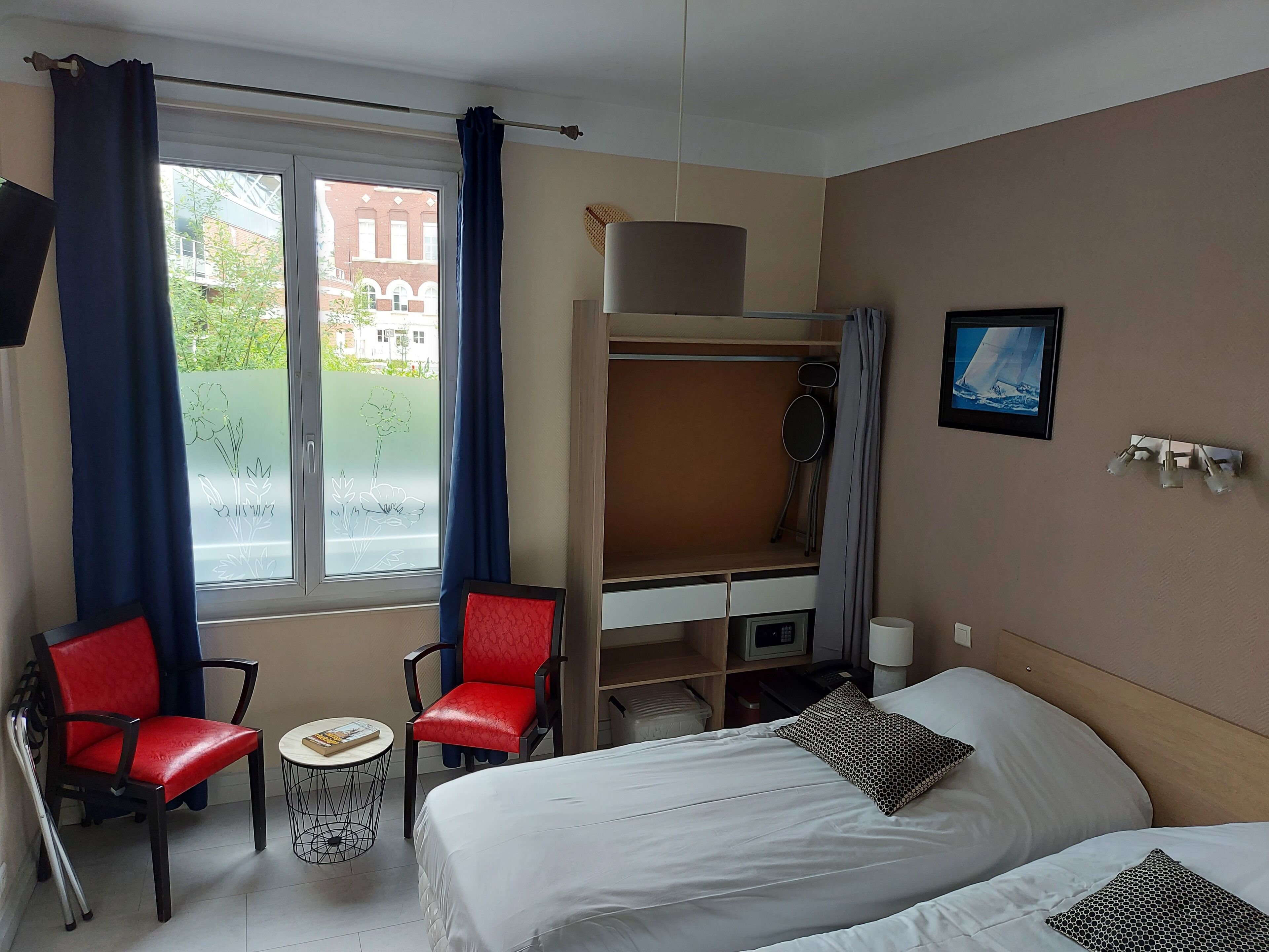 A hotel room with a bunk bed, a desk with a chair, a small table, and a window with curtains.