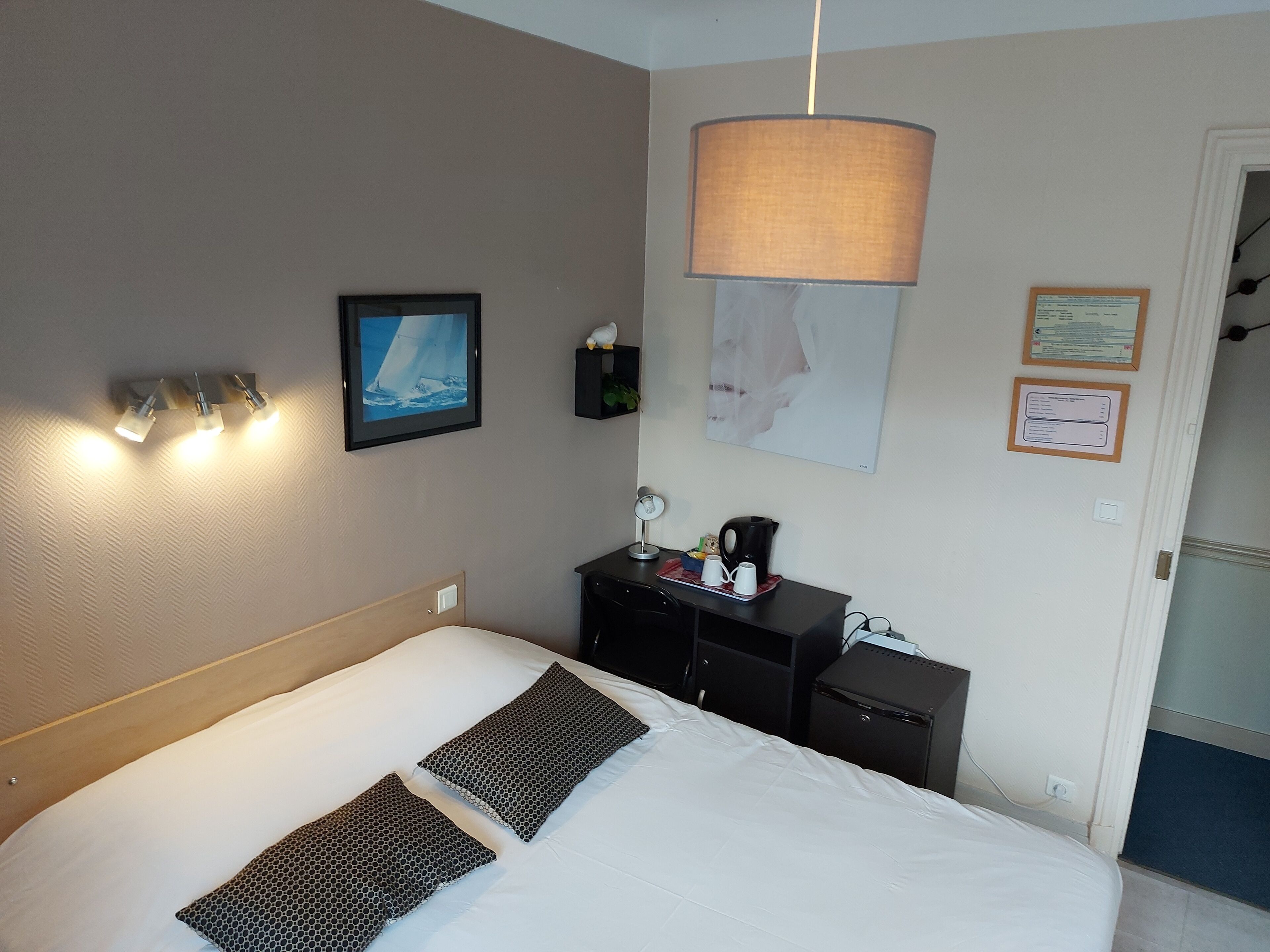Une chambre d’hôtel comprenant un lit, une table de chevet, une lampe et des éléments de décoration fixés au mur.