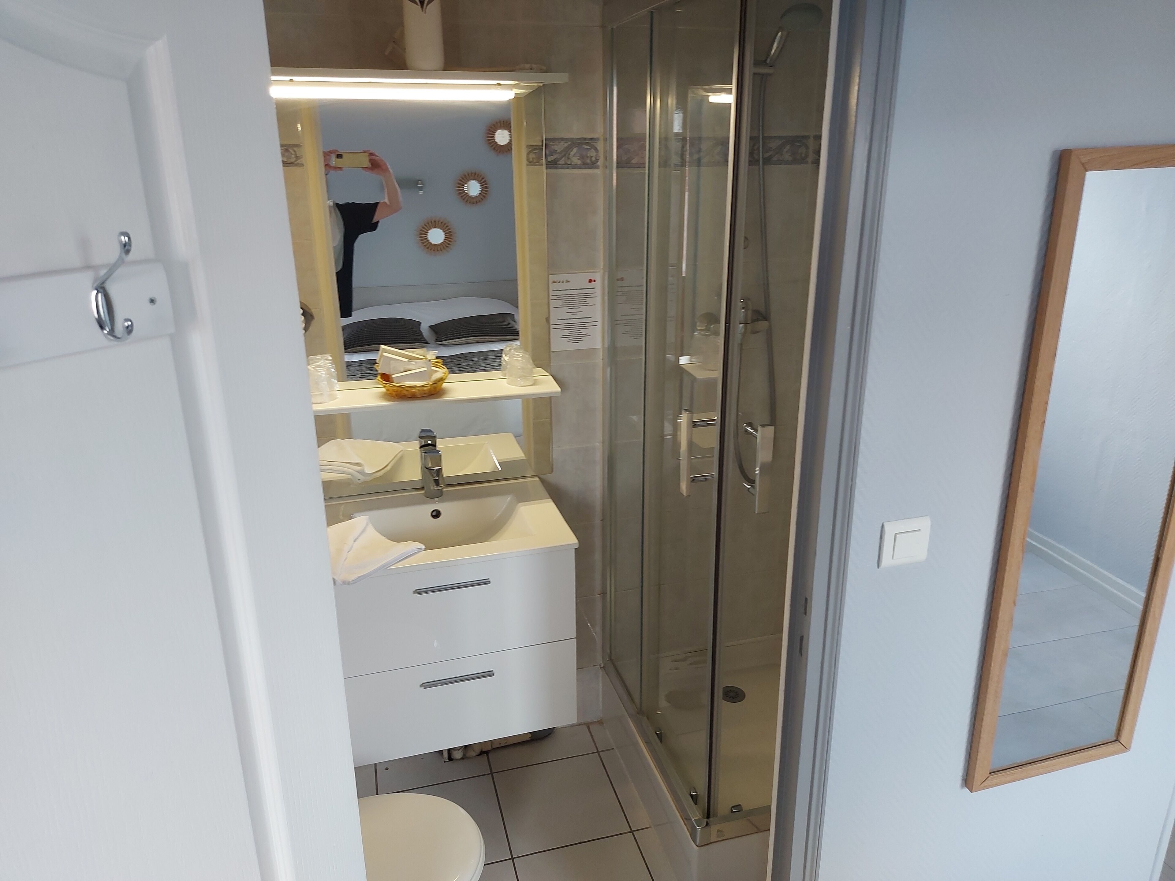 Een moderne badkamer met een douchecabine van glas, een witte wastafel en een spiegel boven de wastafel.