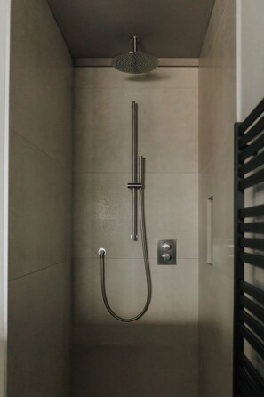 A modern shower with a handheld showerhead and a wall-mounted control panel.