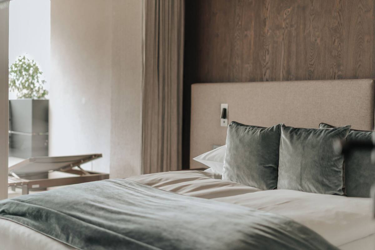 Een moderne hotelkamer met een bed, een nachtkastje en uitzicht op de omgeving.