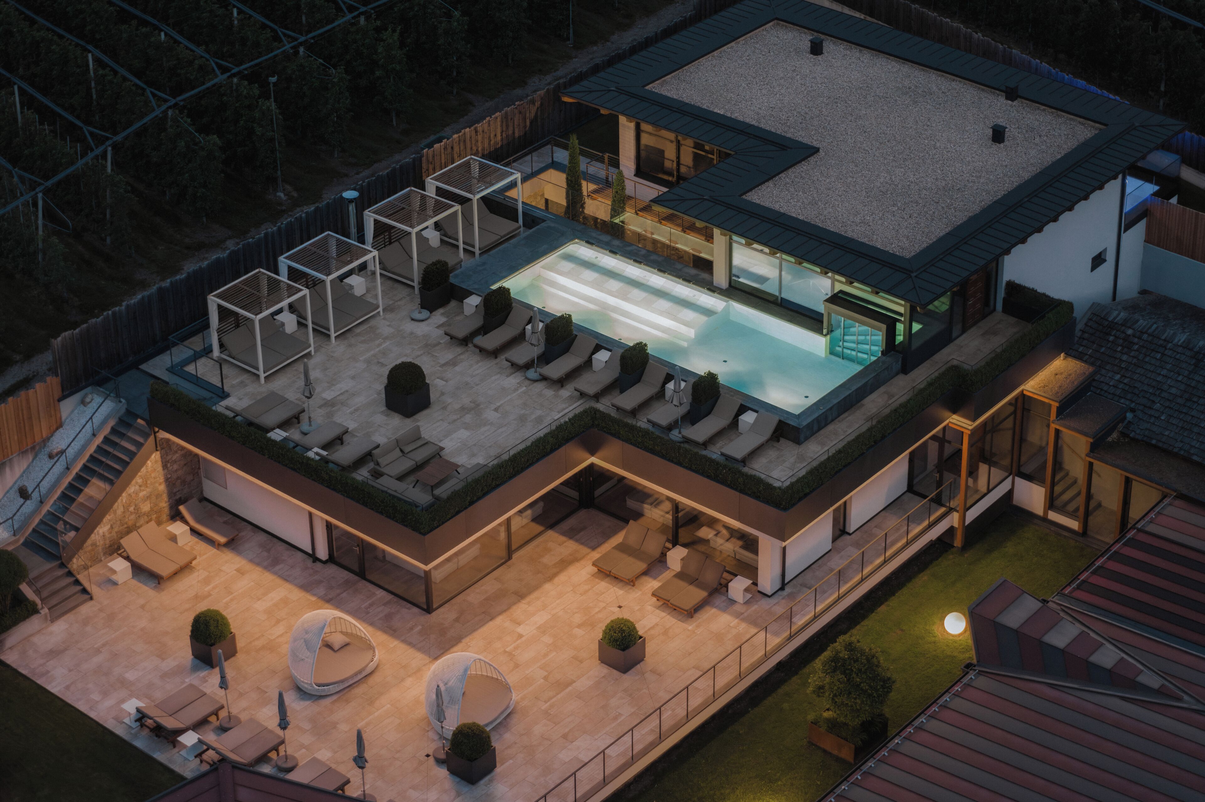 Vista aérea de una casa moderna con piscina en la azotea, mobiliario exterior y un patio cubierto.
