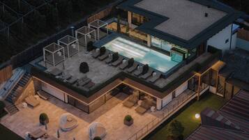 Vista aérea de una casa moderna con piscina en la azotea, mobiliario exterior y un patio cubierto.