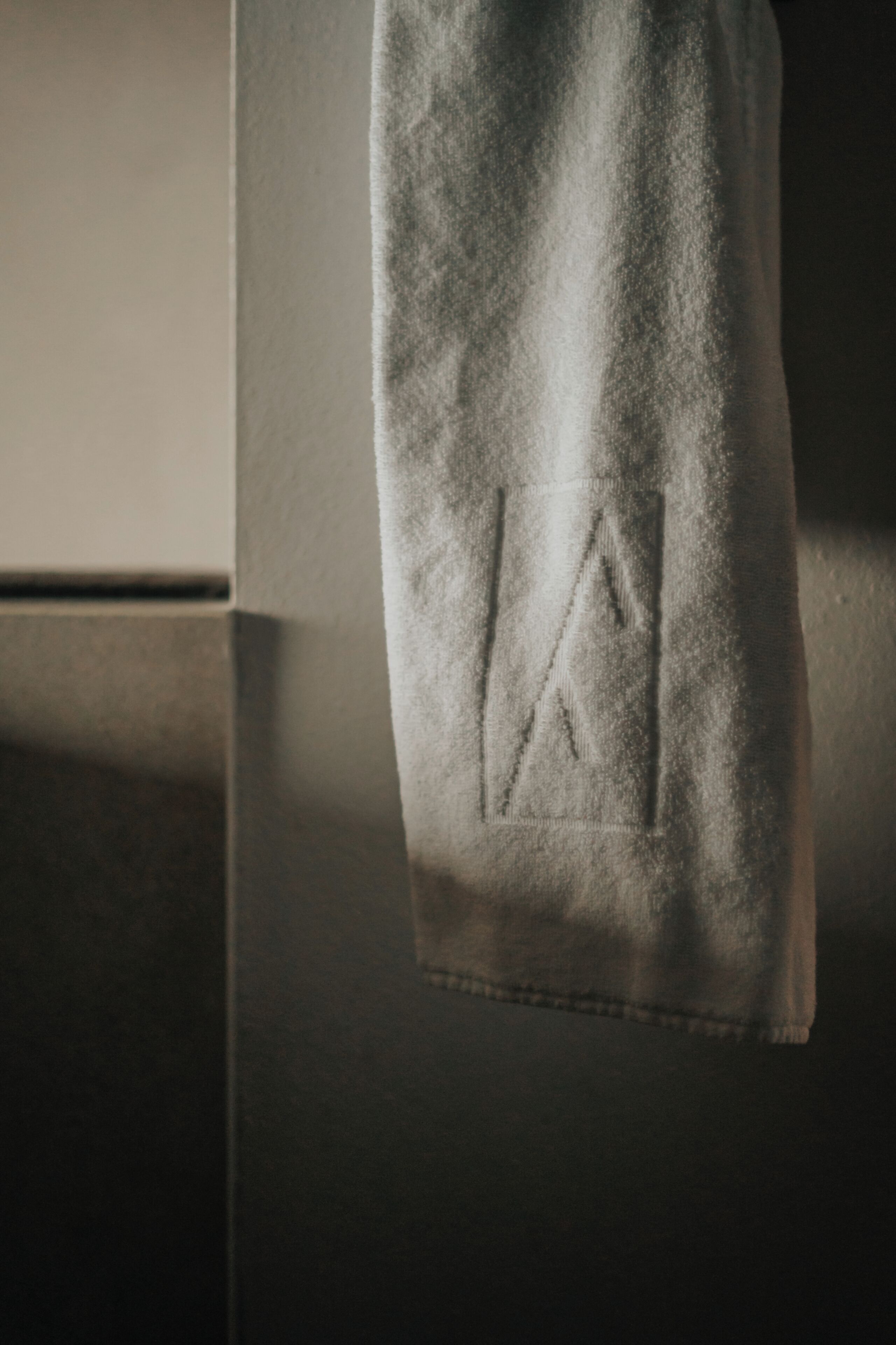 A towel hanging on a wall with a visible embroidered logo.