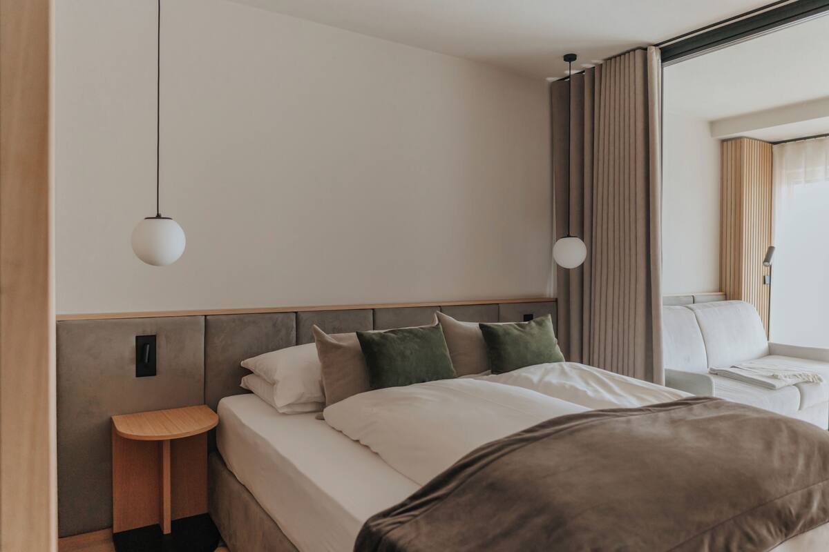 Een moderne hotelkamer met een bed, nachtkastje en uitzicht op de stad.