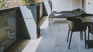 Een modern balkon met een houten plafond, een zithoek met een tafel en stoelen, en uitzicht op bomen.