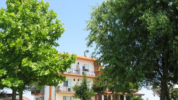 A two-story building with balconies, surrounded by lush greenery and a well-maintained lawn. - B&B Garnì Da Vito (Jesolo)