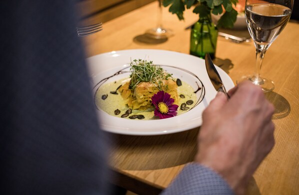 A dining table with a plate of food, a wine glass, and a fork.