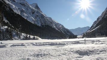 A snow-covered mountain landscape with a clear sky and a bright sun.
