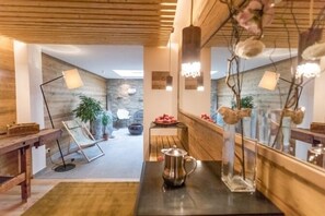 Un interno moderno con travi in legno, una parete in pietra e una superficie riflettente.