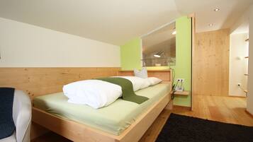 A modern bedroom with a wooden bed, a green wall, and a mirror.