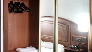 A hotel room with a wooden wardrobe, a bed with white bedding, and a bedside telephone. - Tropical (Puerto de la Cruz)