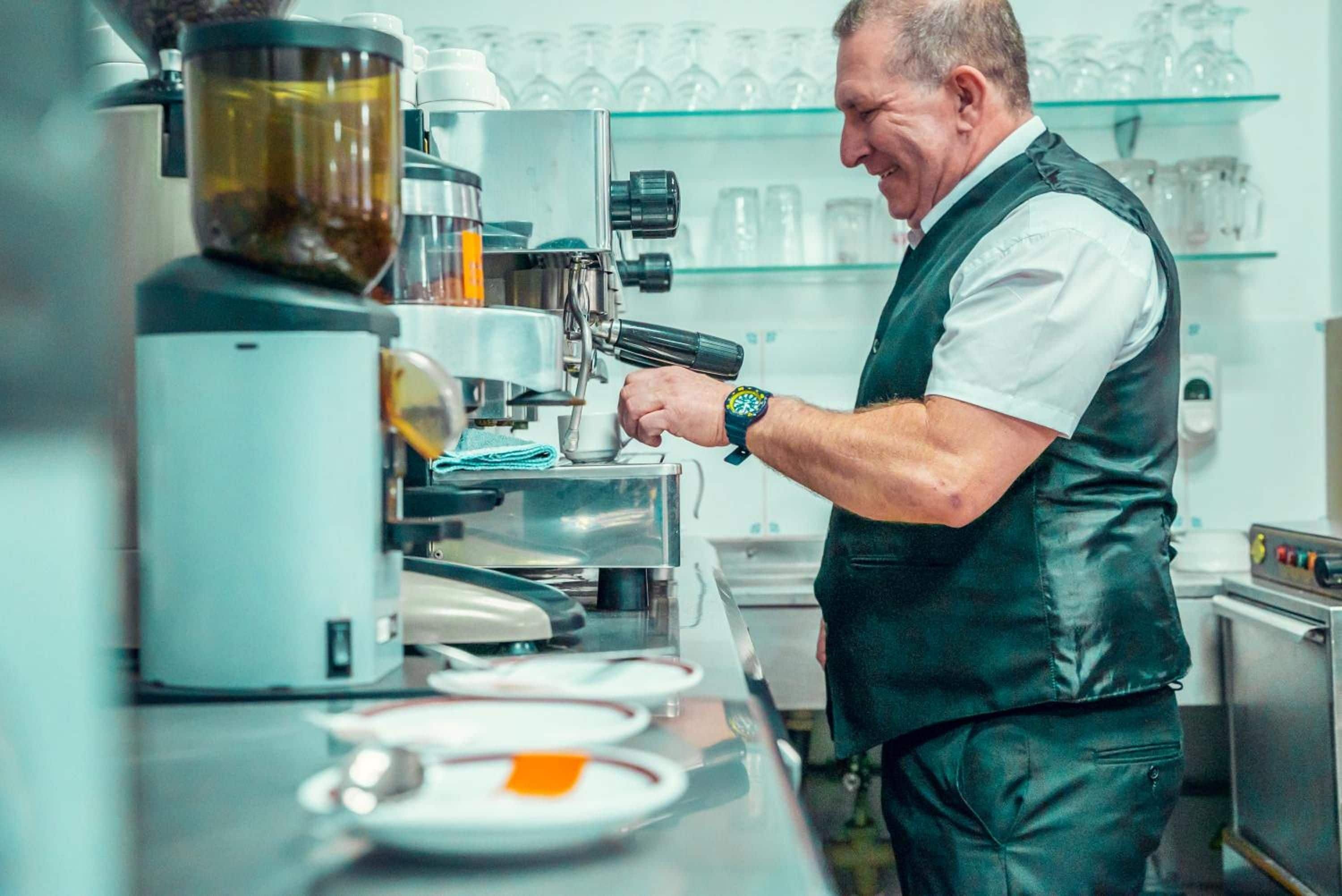 A person operating a coffee machine in a kitchen setting.