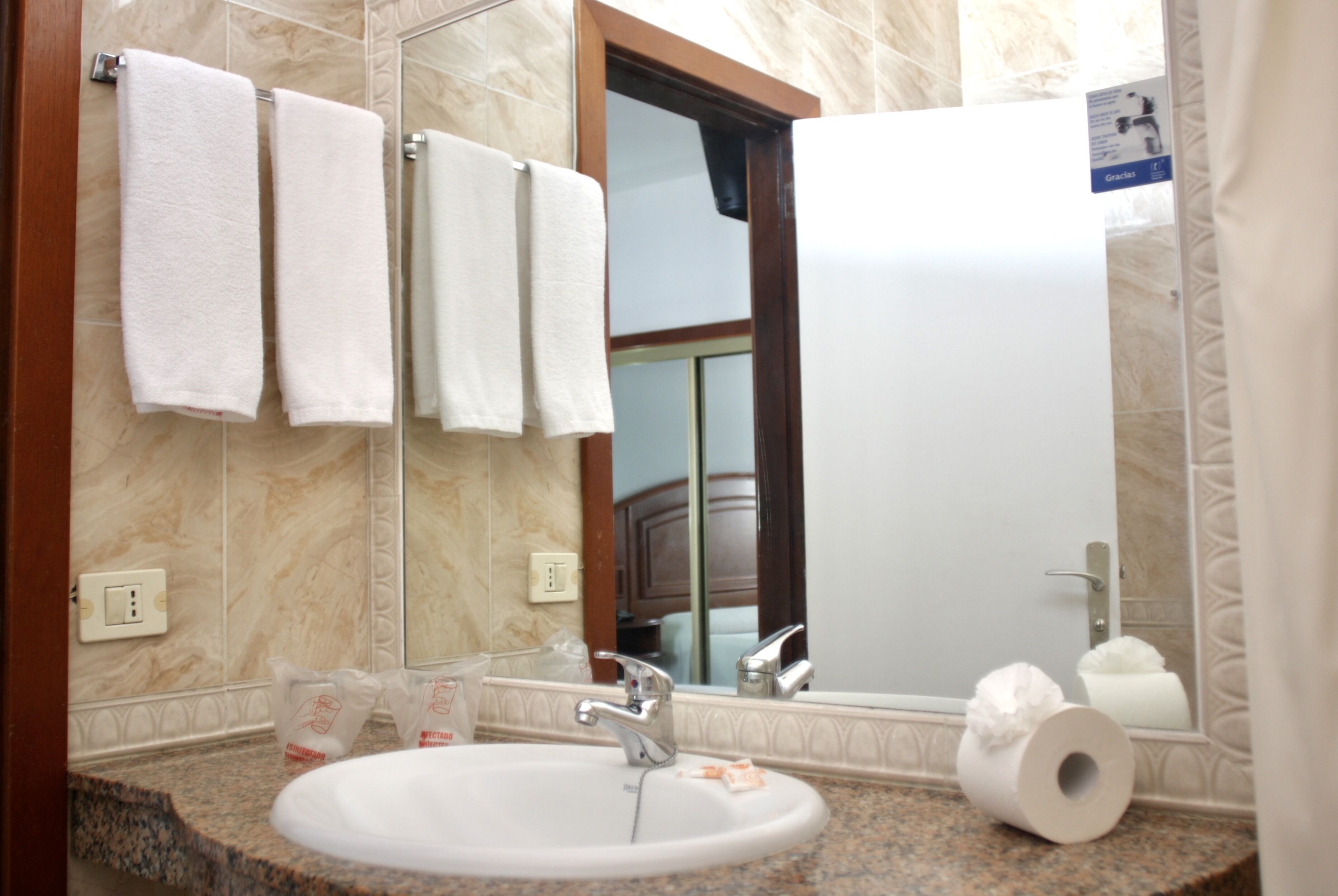 Un baño con lavamanos, espejo y toallas.