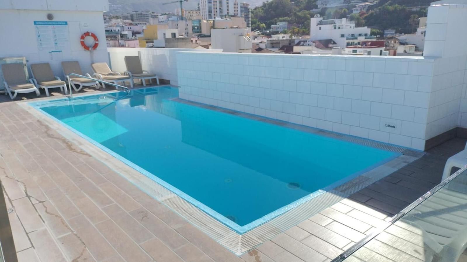 A rooftop swimming pool with lounge chairs and a life ring.