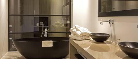A modern bathroom with a large freestanding bathtub, a glass-enclosed shower area, and a vanity with two sinks.