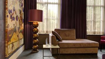 A cozy living room with a sofa, a table with a lamp, and a large painting on the wall.