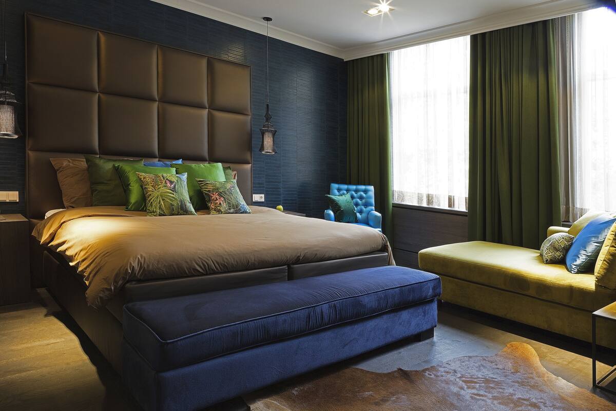 Une chambre à coucher moderne avec un grand lit, un fauteuil bleu et un canapé.