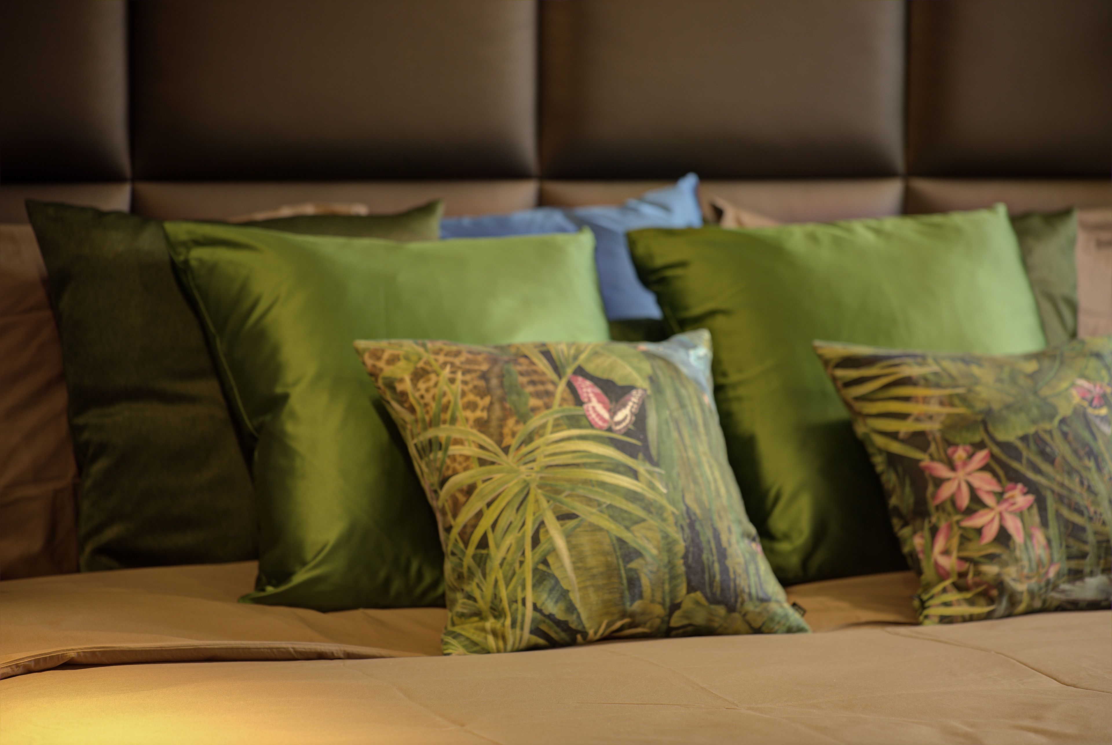 Una cama con muchos almohadones, algunos con motivos florales.