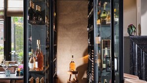 Un interior moderno con un espacio central abierto, flanqueado por estanterías de vidrio que exhiben diversas botellas y objetos decorativos.