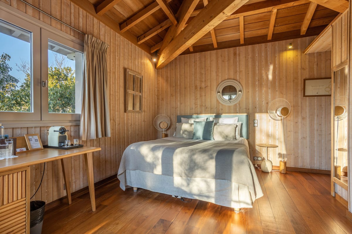 Una habitación de madera con una cama, un escritorio y una ventana.