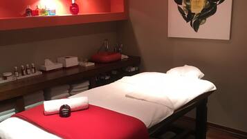 Relax in a serene treatment room with a central bed, wooden bench, and soothing skincare essentials.