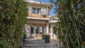 Entrada de un hotel con una terraza de madera, plantas en macetas y un cartel que dice 'HOTEL & SPA'.