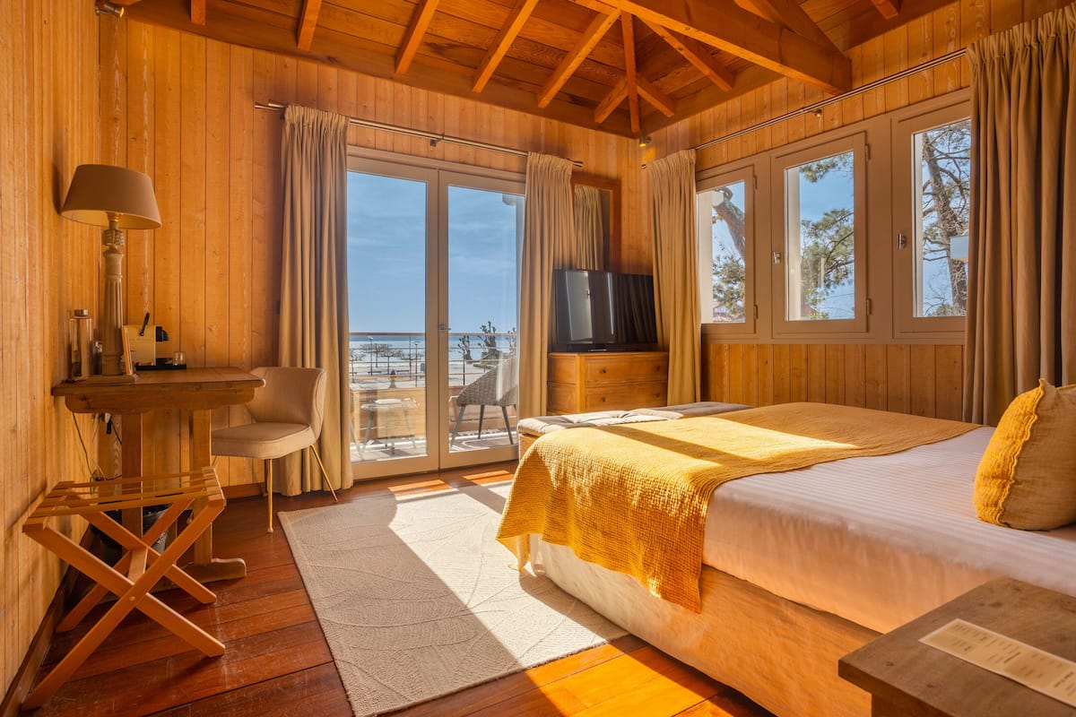Un dormitorio de cabaña de madera con una cama, un televisor, un escritorio y una silla.