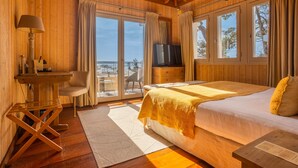 Un dormitorio de cabaña de madera con una cama, un televisor, un escritorio y una silla.