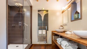 Un baño moderno con ducha de vidrio, tocador de madera con lavamanos grande y un perchero para toallas.