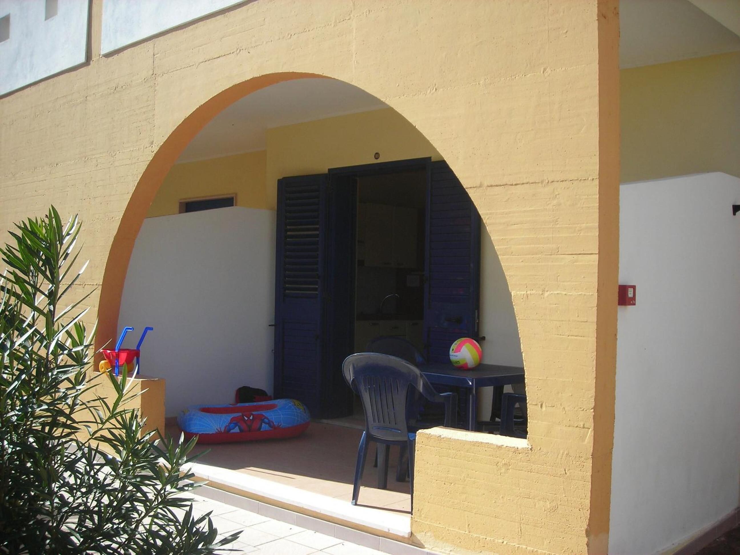 Un área de estar al aire libre con una mesa y sillas, una pelota de playa y un inflable de Spiderman.