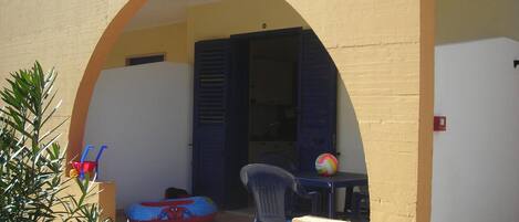 Un área de estar al aire libre con una mesa y sillas, una pelota de playa y un inflable de Spiderman.
