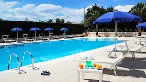 Ein Poolbereich mit Liegestühlen, Sonnenschirmen und einem Tisch mit Früchten und einem Handtuch.