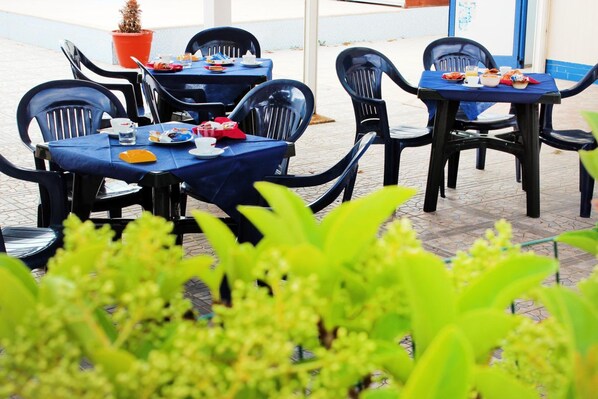 An outdoor dining area with tables and chairs, surrounded by greenery. - Oasi Salento Residence Hotel (Melendugno)